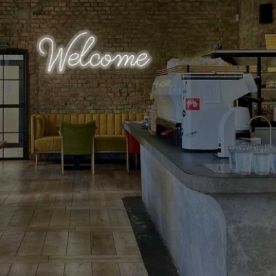 Espaço interior de café com balcão em betão, cadeiras estofadas e iluminação neon