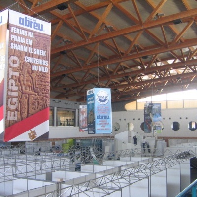 Pavilhão de feira comercial vazio com banners promocionais de destinos turísticos