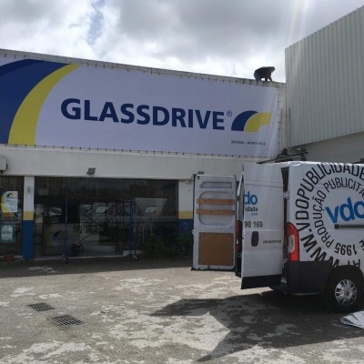 Fachada da loja Glassdrive com carrinha branca estacionada e céu nublado
