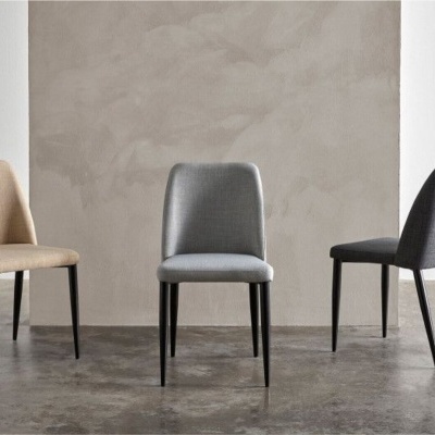 Três cadeiras estofadas em tons neutros com pernas pretas