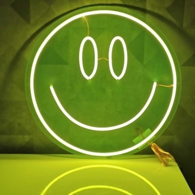 Neon verde em forma de sorriso sobre parede escura com padrão geométrico e mesa verde clara