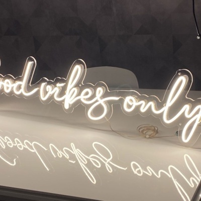 Placa de luz de néon com o texto 'Good vibes only' em letras cursivas brancas em superfície branca.