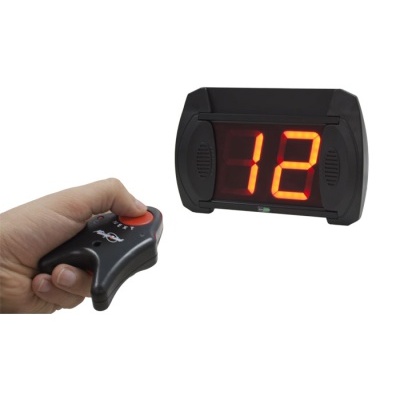 Relógio digital preto com números vermelhos e controle remoto na mão