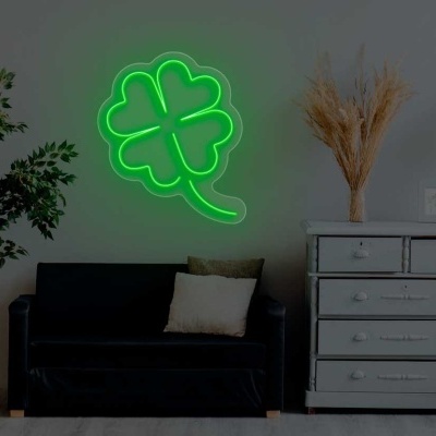 Sala com sofá preto, cómoda cinza, candeeiro de pé e néon verde em forma de trevo.