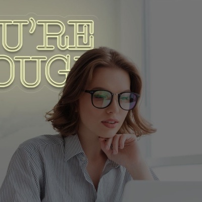 Mulher com óculos a trabalhar diante de um computador com texto luminoso ao fundo