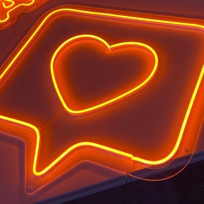 Sinal de néon laranja com coração e texto 'TAFA' na parede