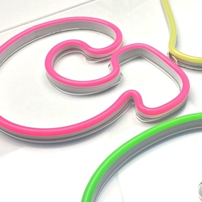 Placa acrílica com letras em néon rosa, amarelo, azul e verde