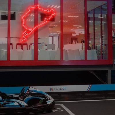 Pista de corrida de karts com dois karts pretos e janela com luz de néon vermelha em forma de casaco