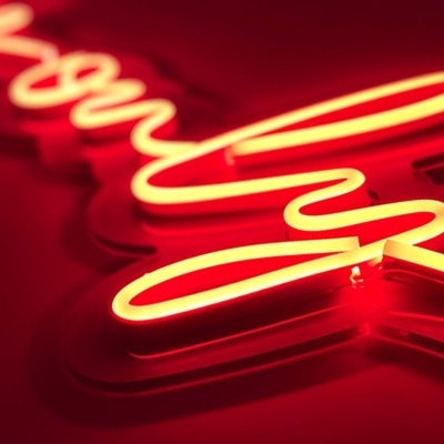 Letreiro neon vermelho em escrita cursiva sobre fundo vermelho