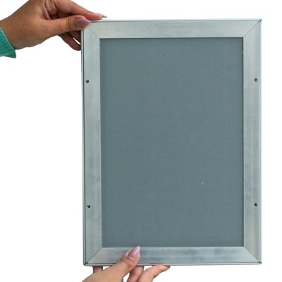 Moldura prateada em metal segurada por duas mãos com mangas verdes