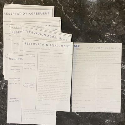 Formulários de reserva em inglês sobre uma superfície preta de mármore.
