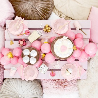 Mesa cor-de-rosa com decoração de festa e almofadas coloridas em volta