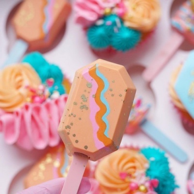 Gelados decorados com linhas coloridas e pequenos pontos dourados em fundo colorido.