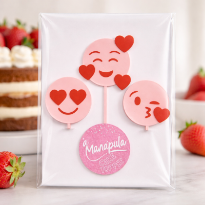 Três cake toppers de emoticons cor-de-rosa com corações vermelhos e etiqueta com texto à Manápula CAKE TOPPER