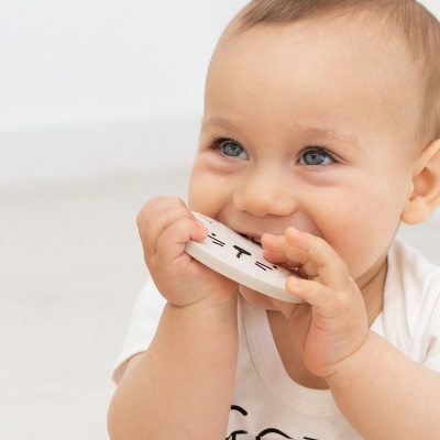 Bebé a morder brinquedo redondo branco com desenho de gato preto