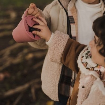 Crianças com casacos felpudos e copos de silicone ao ar livre