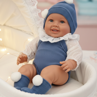 Boneca bebé realista vestida com roupa azul e branca, sentada numa moisés branca com renda.