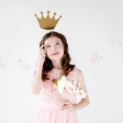 Criança com vestido rosa a segurar coroa e coração dourados em fundo branco com pássaros