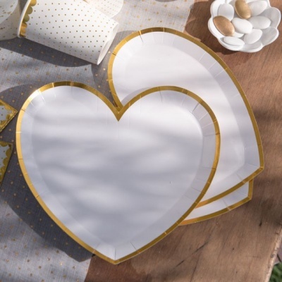 Pratos descartáveis coração com borda dourada sobre mesa com toalha cinza e copos brancos