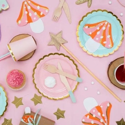 Mesa decorada com pratos e utensílios de festa com padrão de cogumelos e decoração rosa