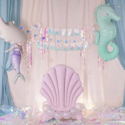 Cenário decorativo com balões de sereia e cavalo-marinho, concha rosa e cortinas azul e rosa