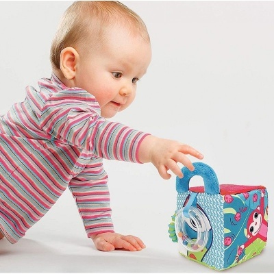 Bebé a alcançar cubo de brinquedo de tecido colorido com alça azul