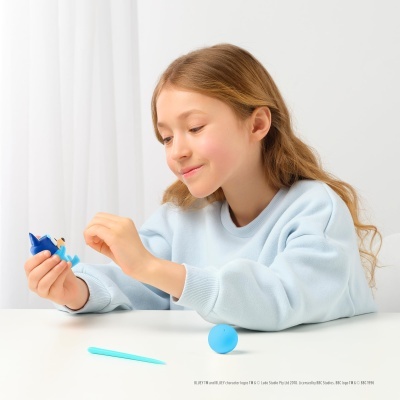 Criança a brincar com figura da personagem Bluey azul num ambiente branco minimalista