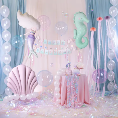 Decoração de festa infantil com balões de sereia e cavalo-marinho e cadeira em forma de concha rosa