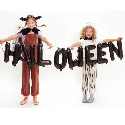 Crianças com traje de Halloween segurando balões negros com a palavra HALLOWEEN.