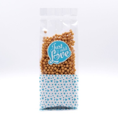 Pacote transparente com grãos castanhos e etiqueta azul Just add Love