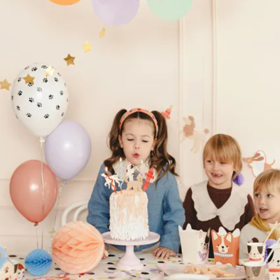 Crianças celebrando festa com bolo e decoração colorida e temática de animais