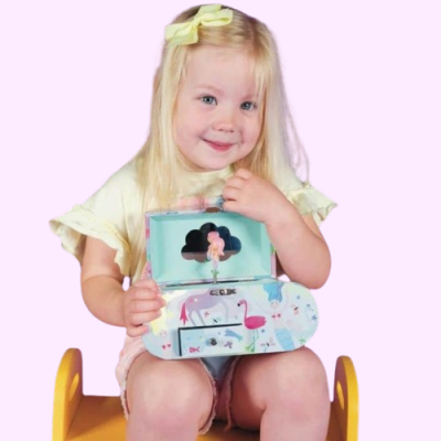 Criança loira segura caixa de música azul com flamingos e desenhos coloridos