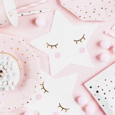 Artigos de festa rosa e branco com estrelas douradas e guardanapos em forma de estrela com olhos fechados