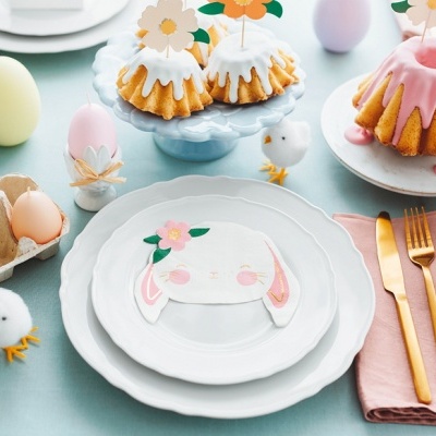 Mesa decorada para Páscoa com pratos, talheres dourados, guardanapo rosa e ovos coloridos