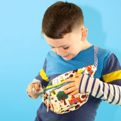 Criança com camisola azul a abrir pochete colorida com desenhos infantis