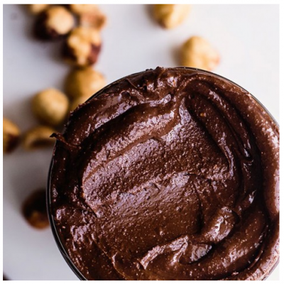 Pote aberto com creme de chocolate e avelãs ao redor