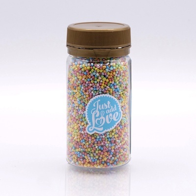 Frasco com tampinha castanha cheio de pequenas esferas coloridas com etiqueta azul e texto 'Just add Love'