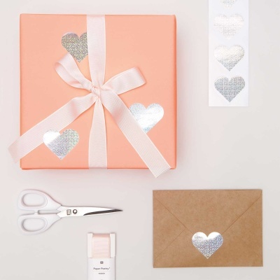 Caixa de presente cor de pêssego com fita rosa e autocolantes prateados em forma de coração