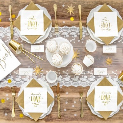 Mesa de festa decorada com elementos brancos, castanhos e dourados em cima de mesa de madeira