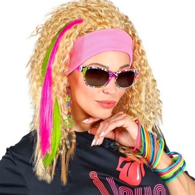Mulher com óculos de sol coloridos, faixa rosa na cabeça, pulseiras coloridas e cabelo loiro com mechas coloridas.