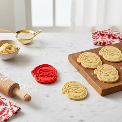 Vários biscoitos em forma de Papai Noel e acessórios de cozinha numa bancada branca