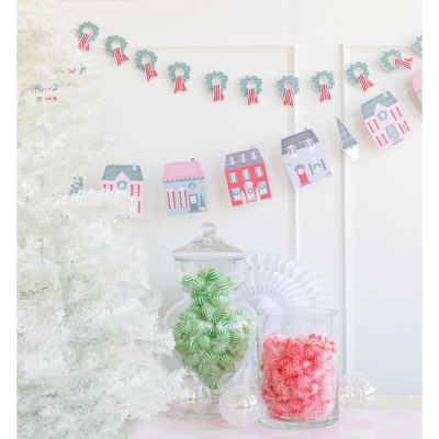 Guirlanda decorativa de papel com casas e árvores, árvore de Natal branca, frascos com doces verde e rosa