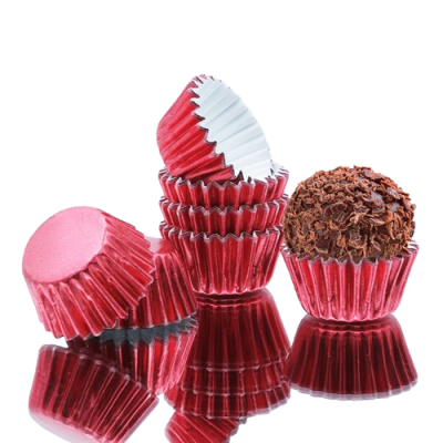 Forminhas vermelhas metálicas para bolos pequenos com brigadeiro em uma delas sobre superfície preta refletora