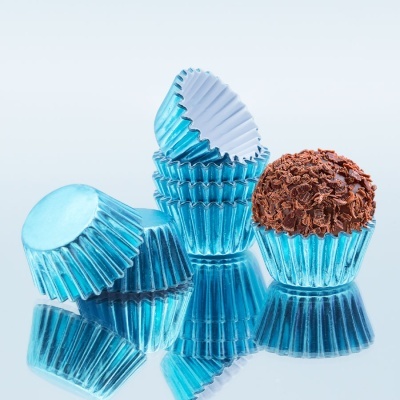 Formas de papel azul metálico para doces com um brigadeiro de chocolate em cima