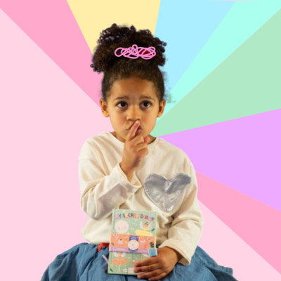 Criança com camisola branca, saia azul, prendedor rosa, segurando embalagem colorida sobre fundo colorido em tons pastel