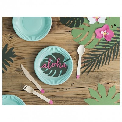 Pratos de papel azul com talheres de plástico sobre mesa de madeira decorada com folhas tropicais e flores