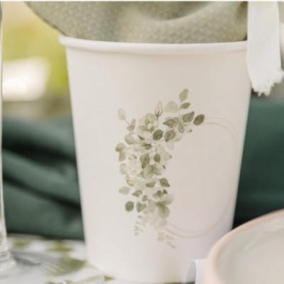 Copo de papel branco com estampa de folhagem verde e guardanapo colocado dentro