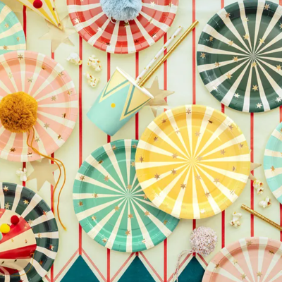 Pratos e chapéus de festa coloridos com padrões de raios e pompons