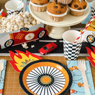 Mesa de festa com pratos, copos, canudos, e decoração temática de corridas de carros