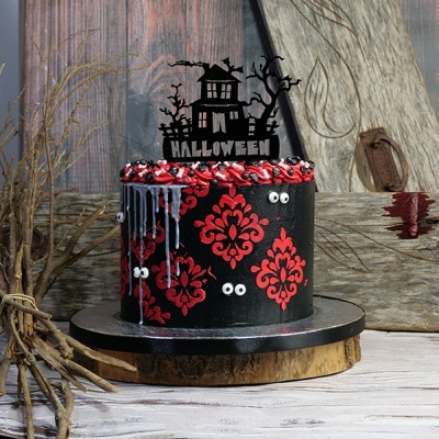 Bolo de Halloween preto com padrões vermelhos e olhos decorativos